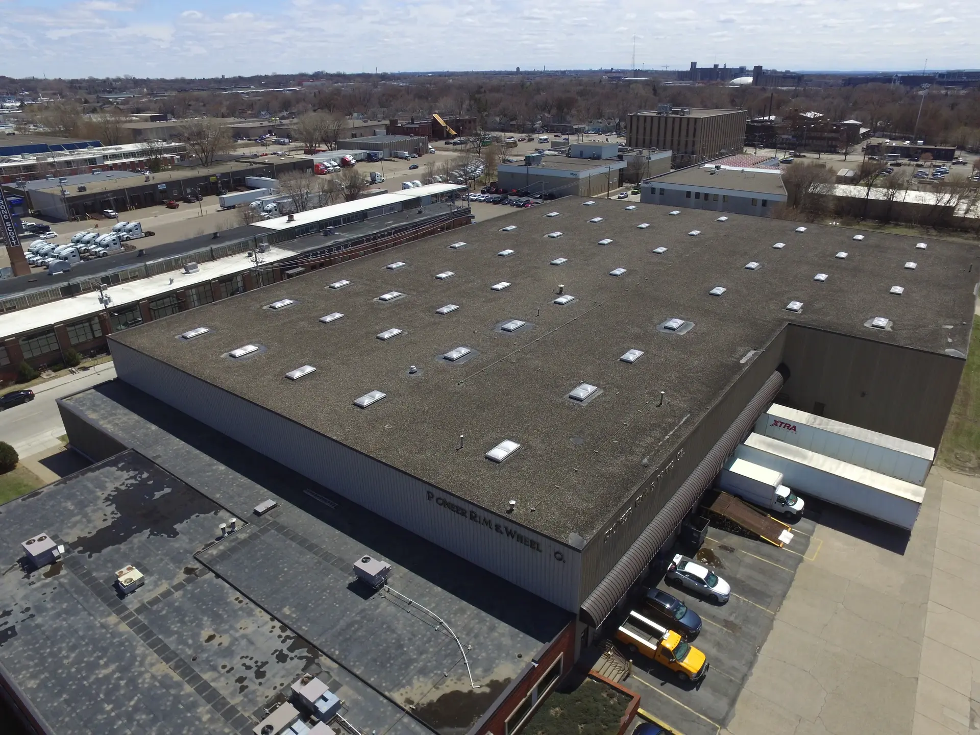 Aerial view of a large flat commercial roof lined with skylights