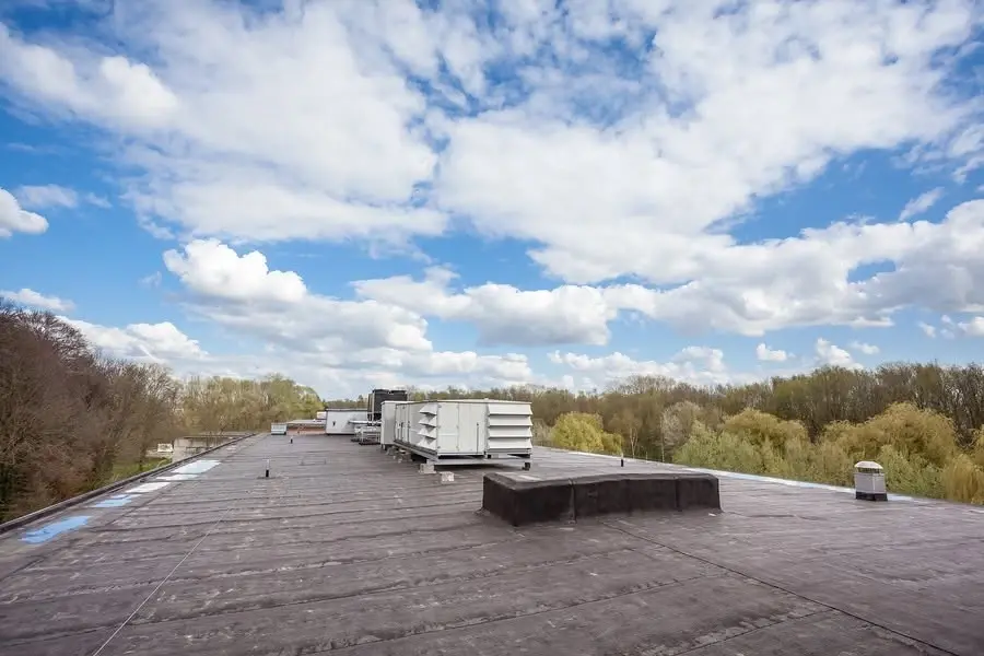 Flat commercial roof with rooftop HVAC units running along the ridge under an open sky