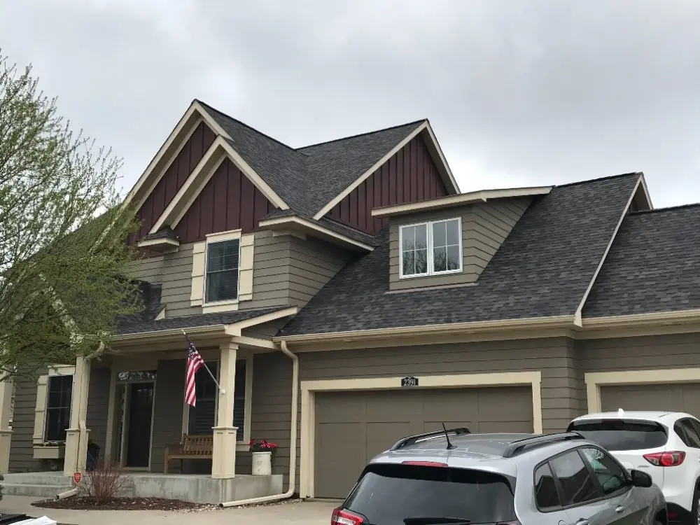 Completed charcoal shingle roof on a two-storey home with taupe siding