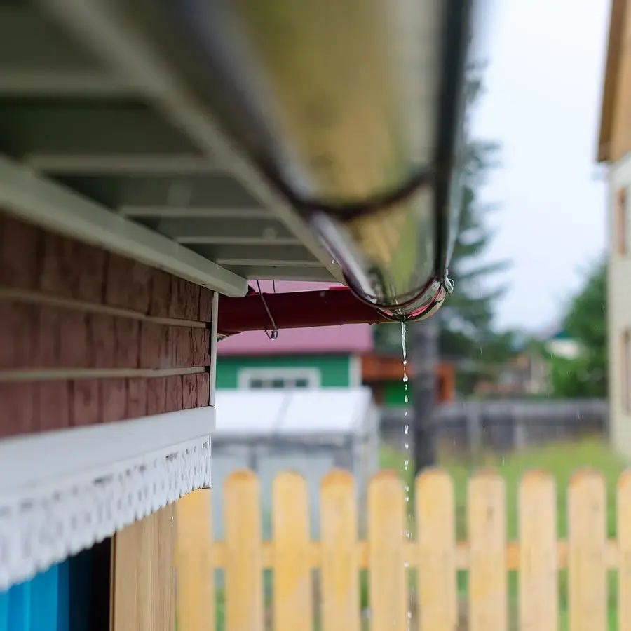 Rainwater running off a gutter and dripping from the downspout joint