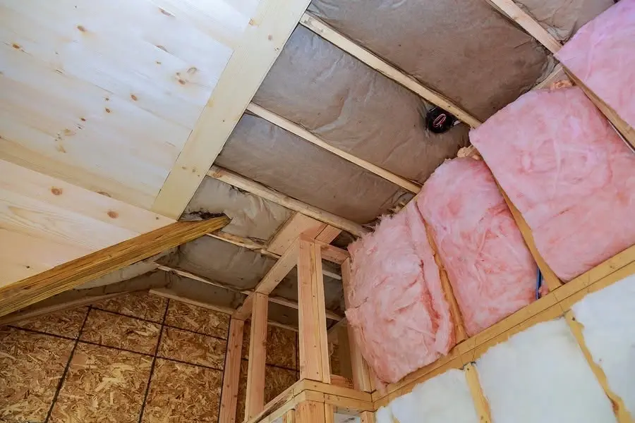 Pink fiberglass batt insulation installed between attic rafters
