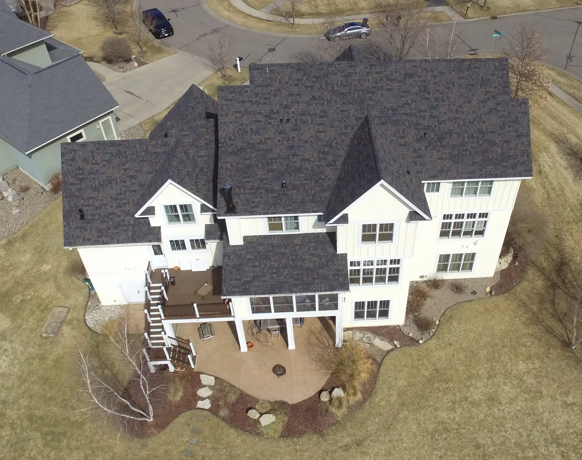 Aerial view of a large white two-story home with a dark shingle roof